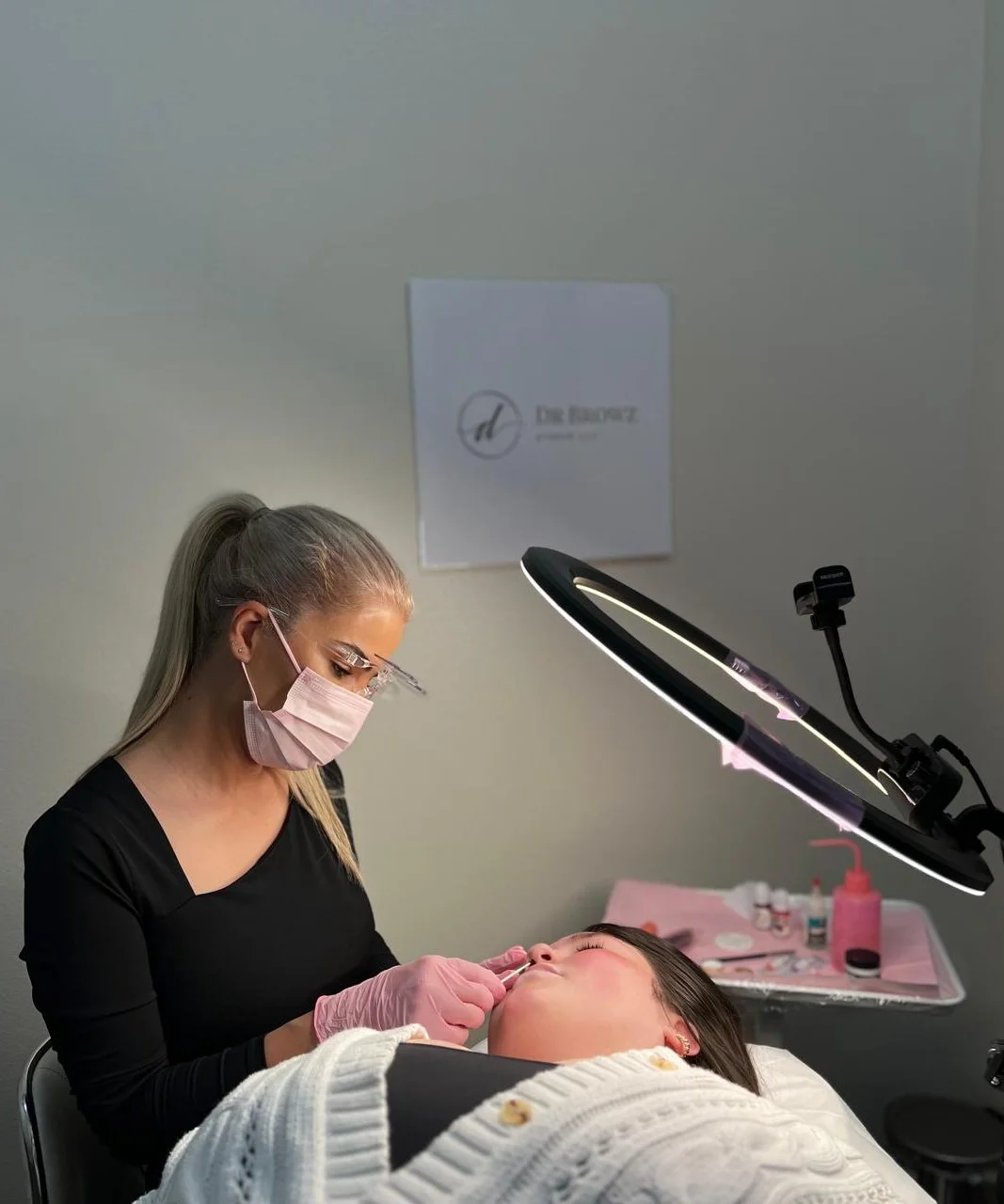 Roya performing a permanent-makeup treatment under a ring light at the Dr Browz studio.
